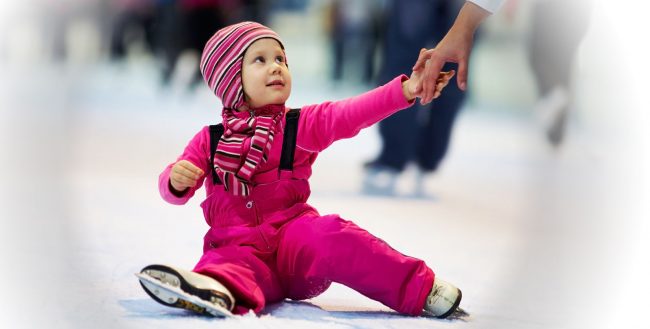 Pikkulapsi opettelee luistelemaan aikuisen avulla.